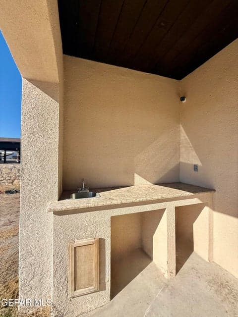 Covered patio with built-in counter and sink, ideal for outdoor cooking.