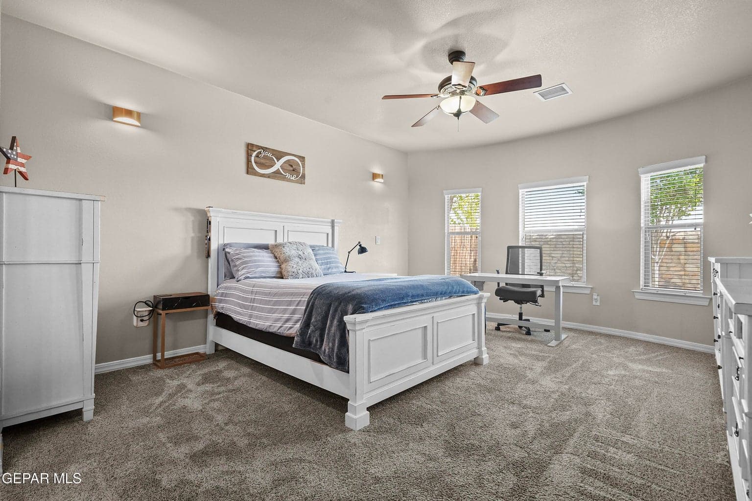 Spacious primary bedroom, carpet flooring, large windows