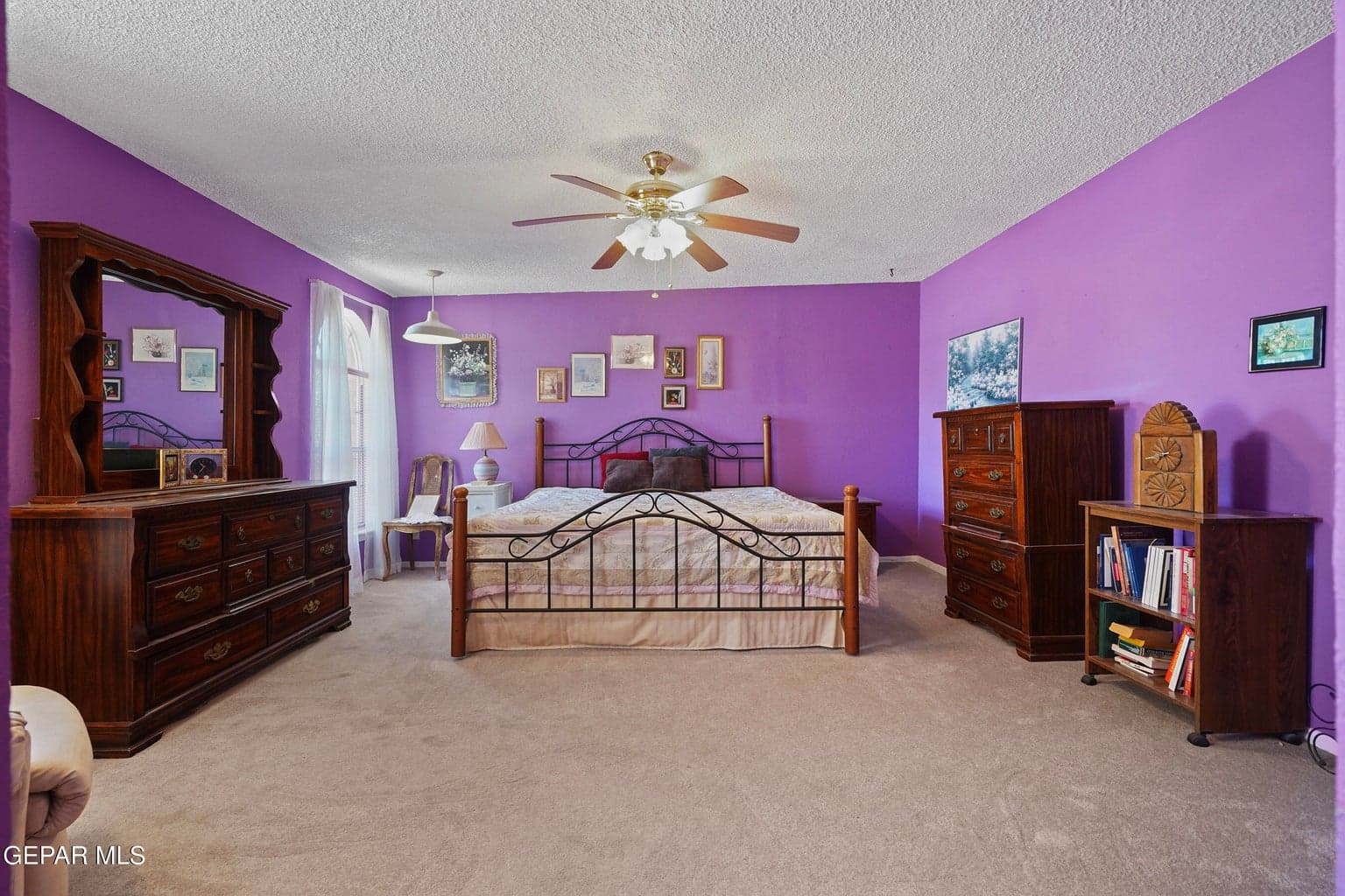 Large bedroom layout, soft carpet flooring, ceiling fan comfort