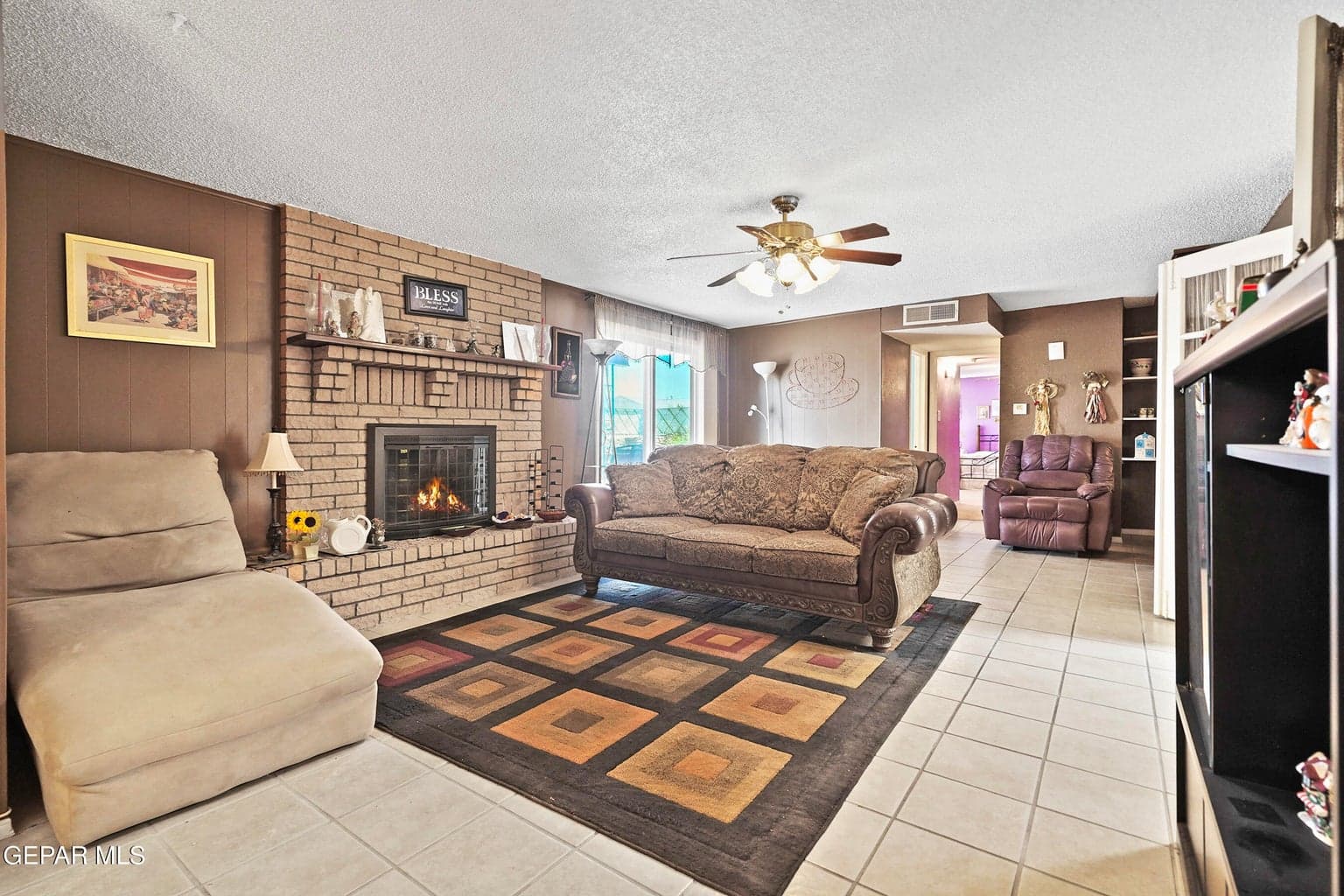 Cozy fireplace centerpiece, durable tile flooring, ceiling fan comfort