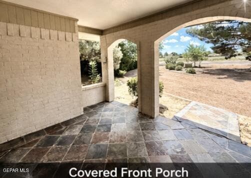Welcoming covered entryway featuring arched architectural details, shaded seating potential, and inviting curb appeal.