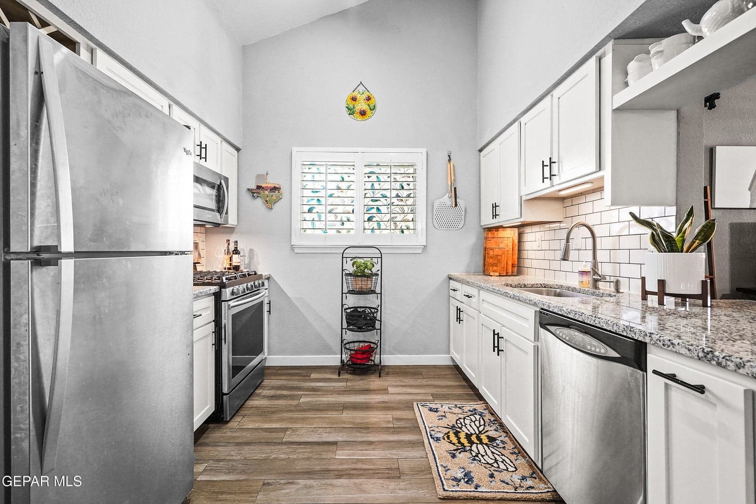 Features granite countertops, wood-like tile flooring, stainless steel appliances, and ample cabinet storage