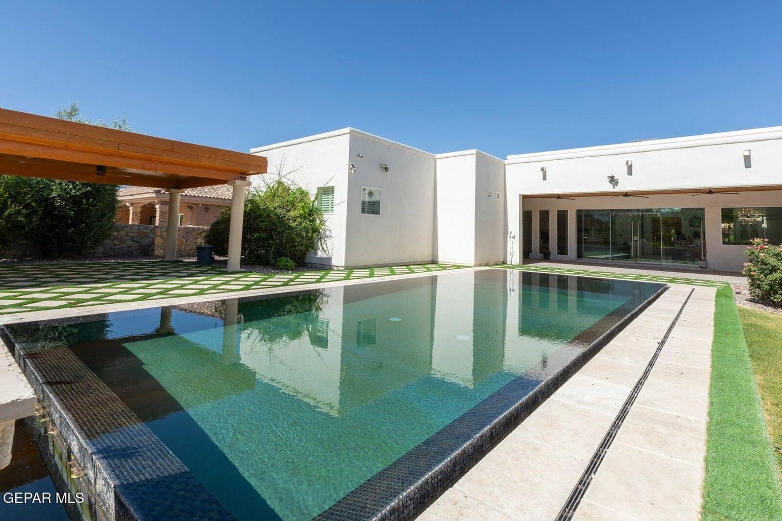 Outdoor living at its finest with infinity-edge pool, covered patio, and full outdoor kitchen.