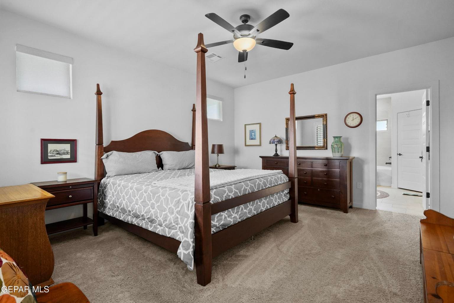 Spacious primary suite features carpet flooring, and a ceiling fan