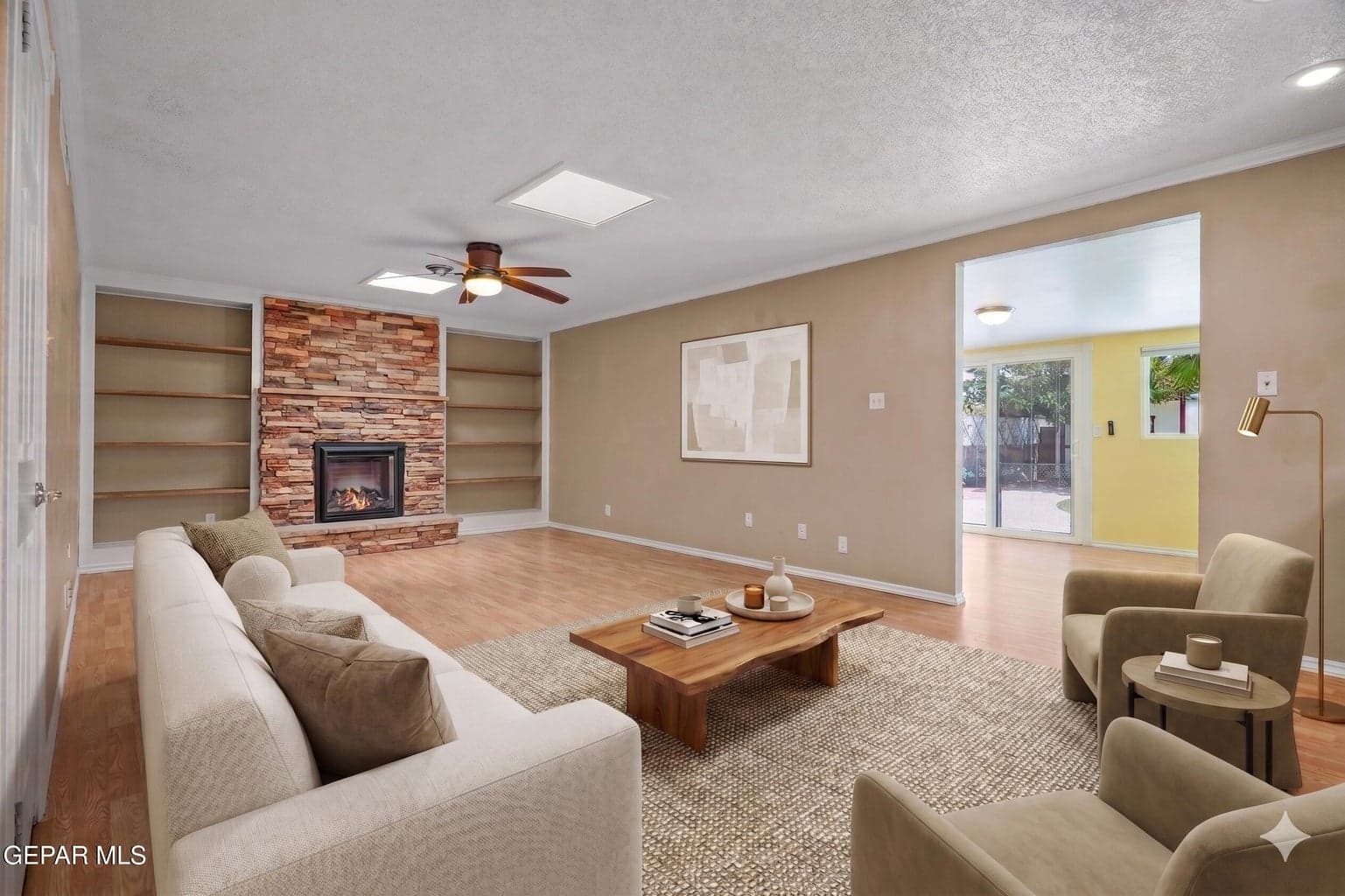 Spacious great room includes vinyl flooring, a cozy fireplace, and a ceiling fan