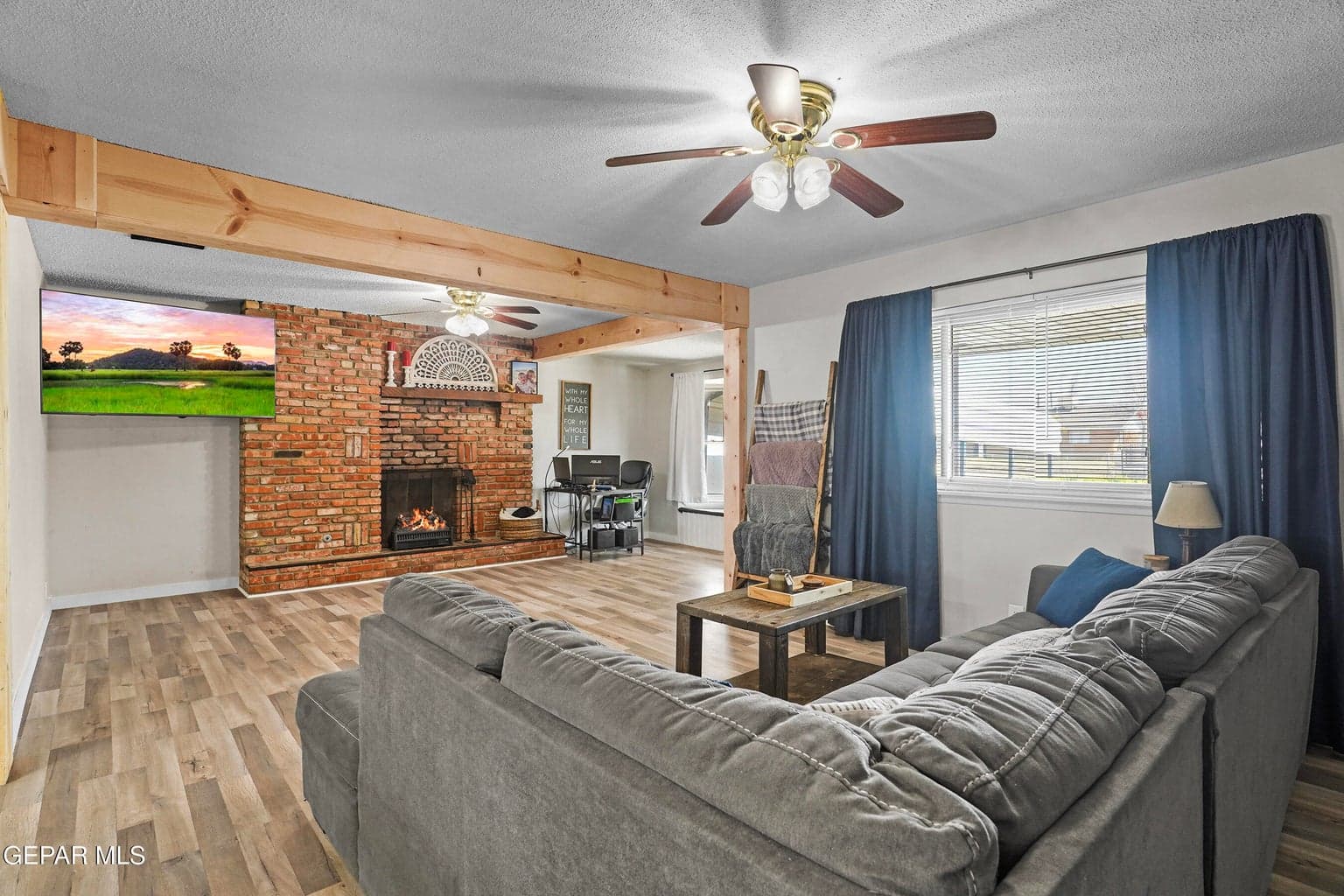 Features a fireplace, ceiling fan, and large windows
