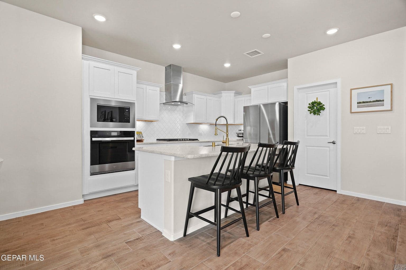 The open gourmet kitchen features modern cabinetry, quartz countertops, a stainless-steel farm sink, decorative tile backsplash, and under-cabinet lighting