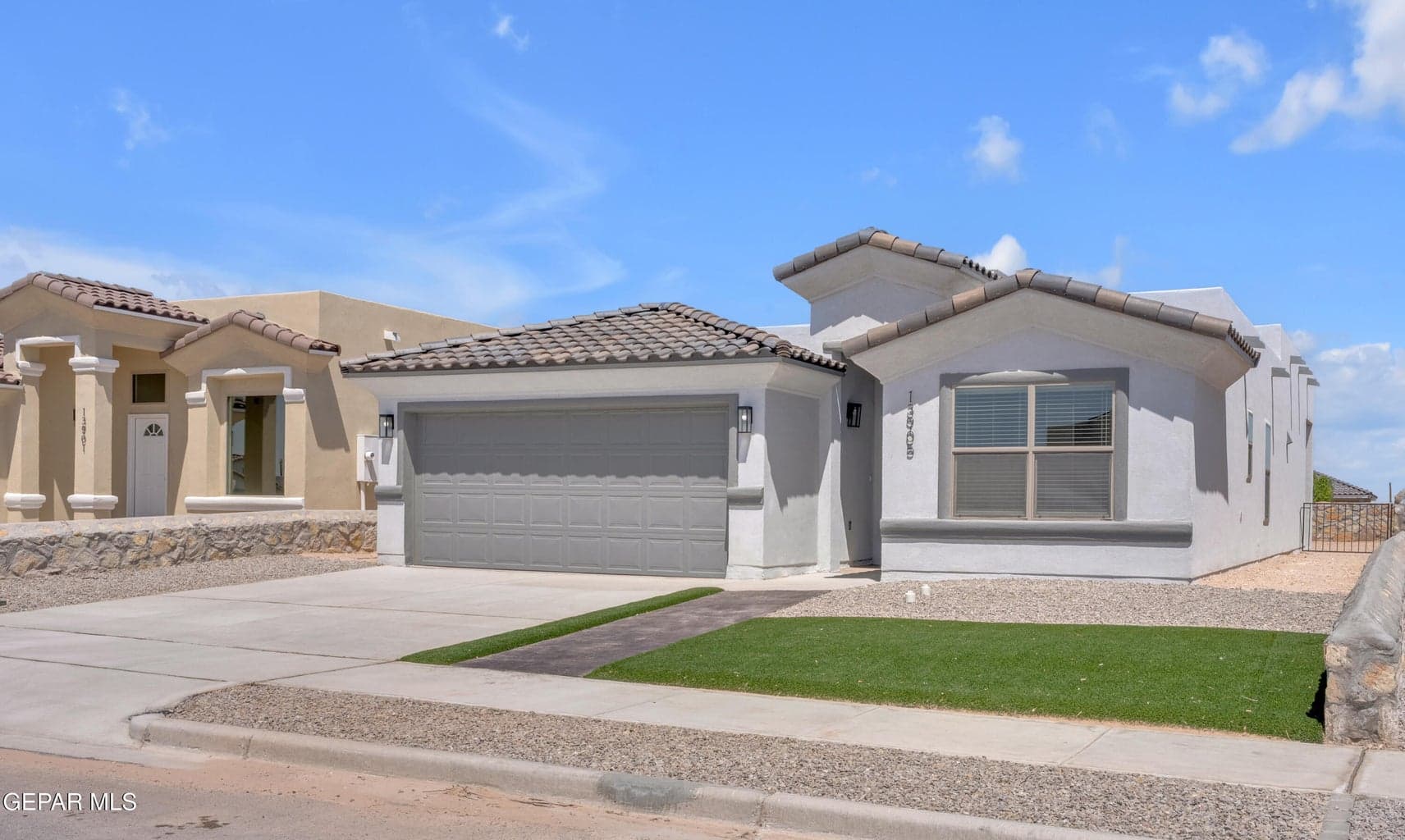 Contemporary exterior with a tile roof, an integrated two-car garage, artificial turf landscaping, and a concrete driveway