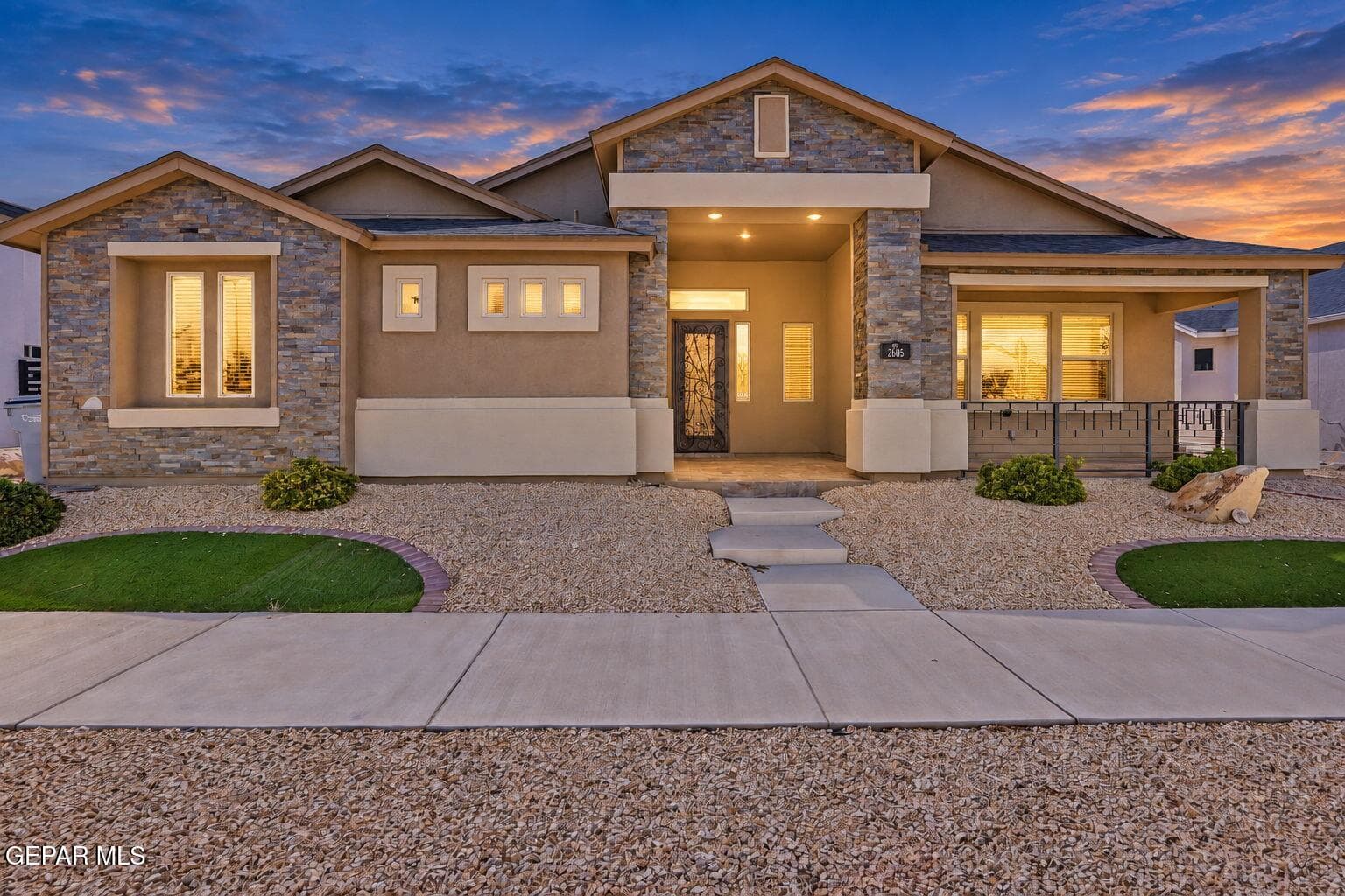 Stucco and stone facade with multiple window styles, covered entry, and a covered porch