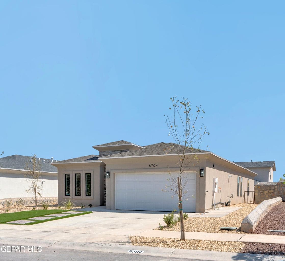 Contemporary exterior with stucco finish, stone accents, and an attached two-car garage