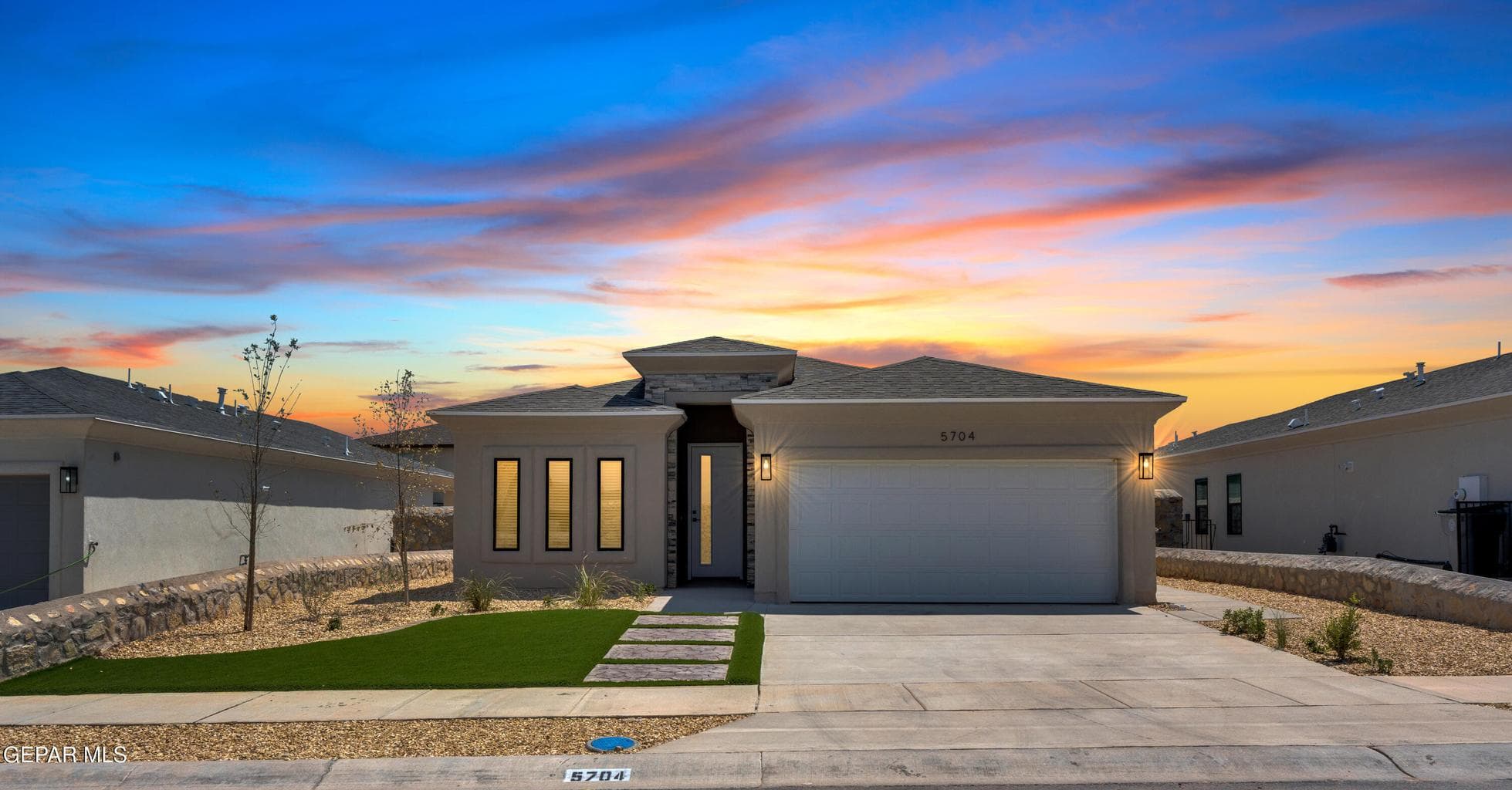 Contemporary stucco exterior with a flat roofline, integrated two-car garage, and a concrete driveway