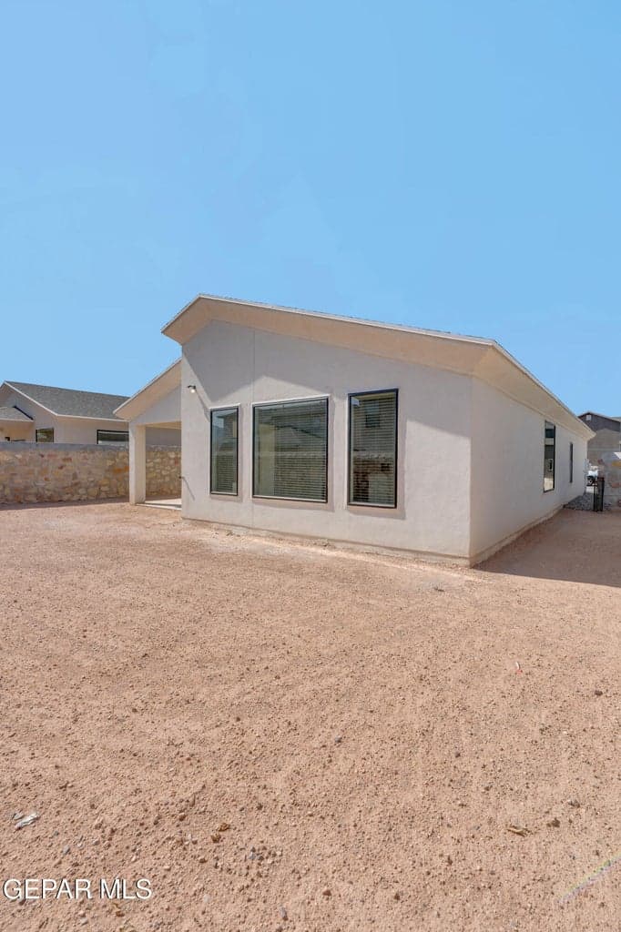 Contemporary exterior with a distinctive slanted roofline, multiple large windows, and a stucco finish