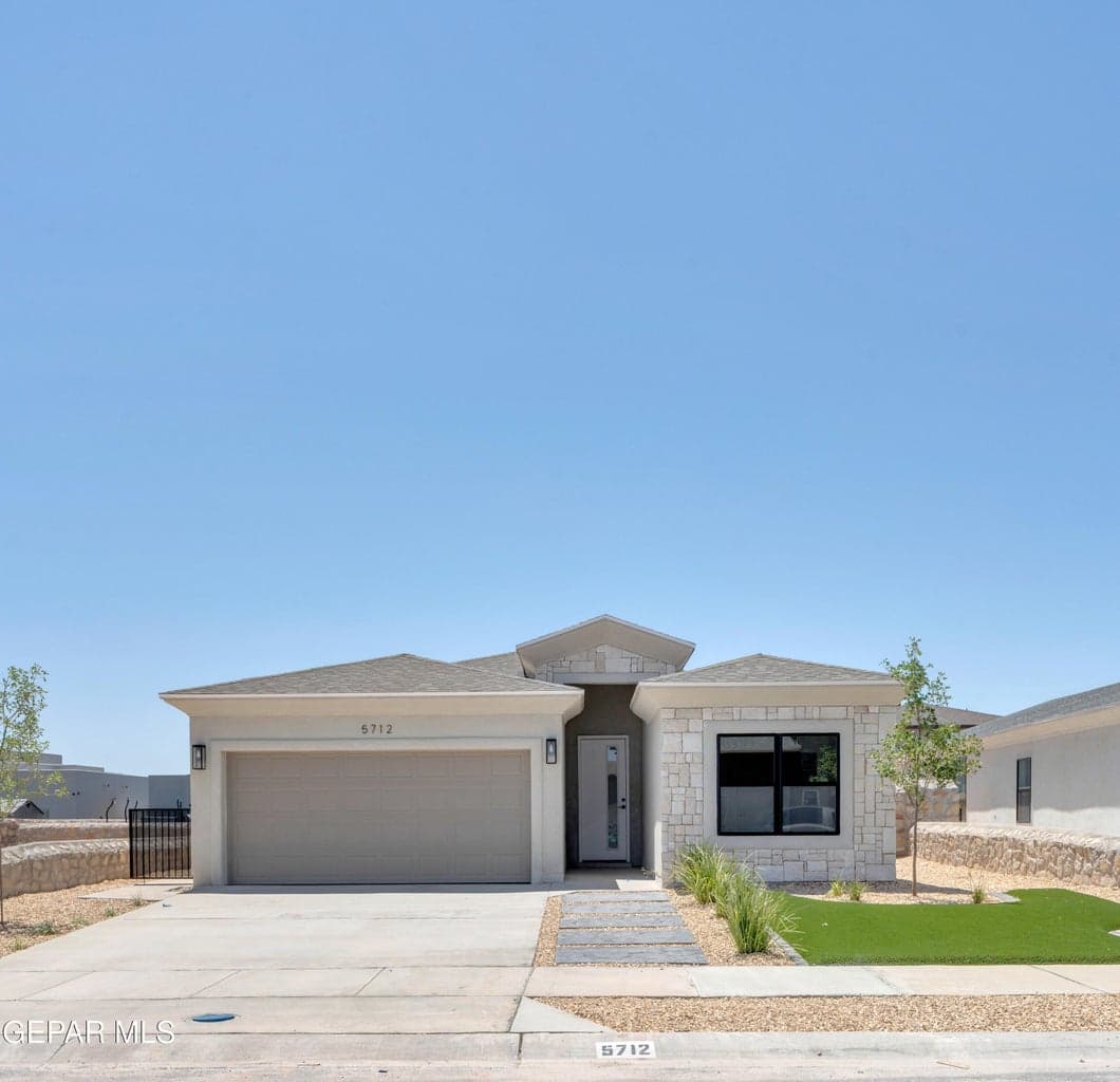 Single-story residence featuring a two-car garage, stone and stucco exterior, and a contemporary entry door