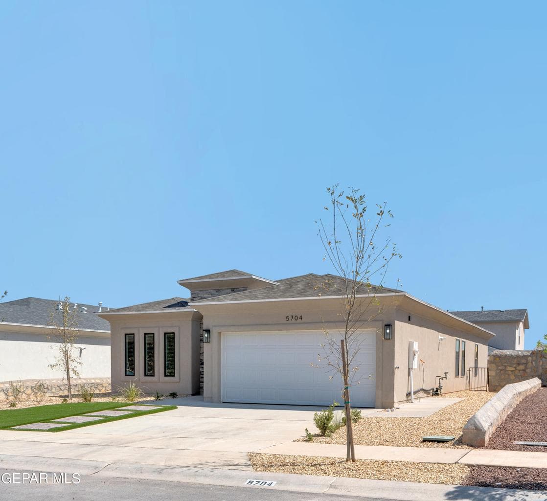 Contemporary exterior with stucco finish, stone accents, and an attached two-car garage