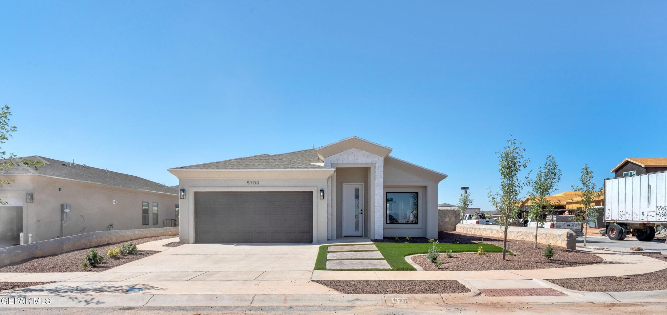 Contemporary stucco exterior with a prominent entry, attached garage, and a paver walkway leading to the front door