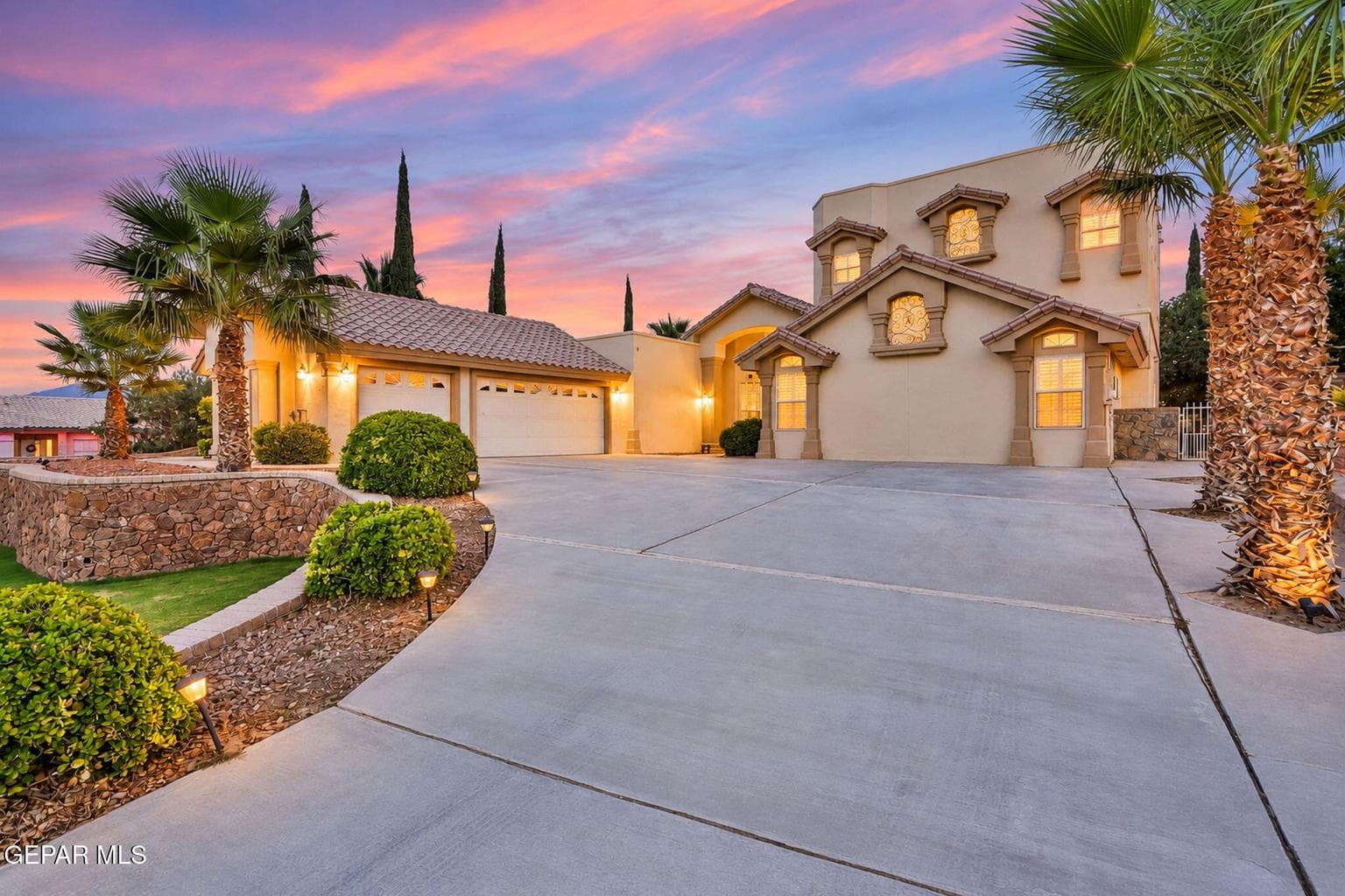 Two-story stucco exterior with arched window details, a tiled roof, and an attached two-car garage