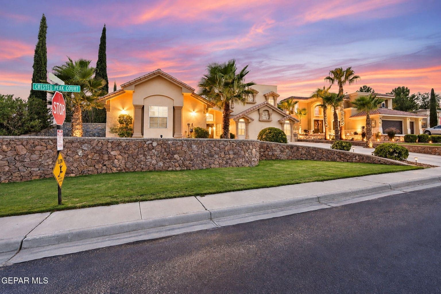 Stucco exterior, stone retaining walls, and mature landscaping