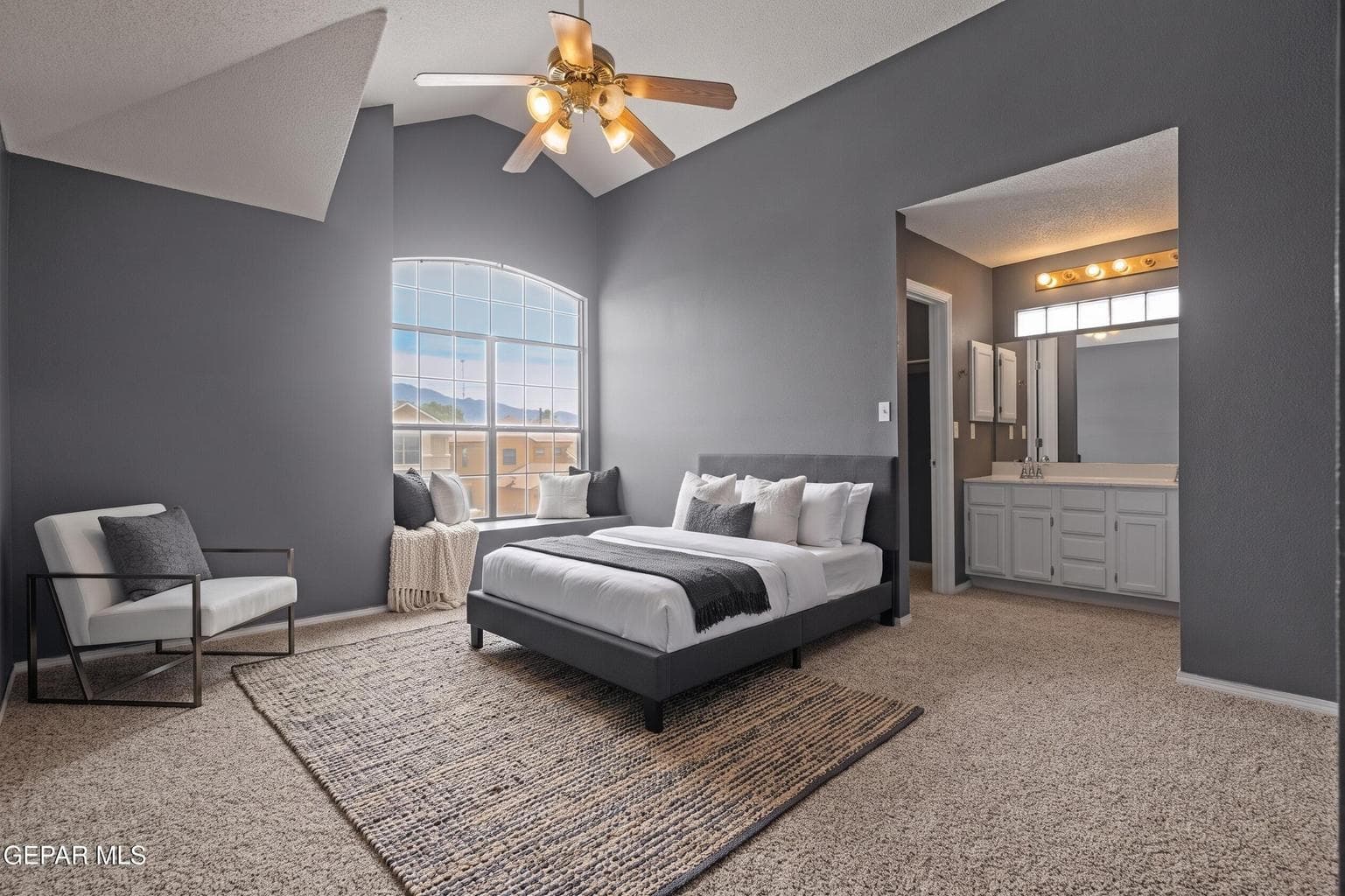 Located upstairs, the primary suite features carpet flooring, vaulted ceilings, and a ceiling fan
