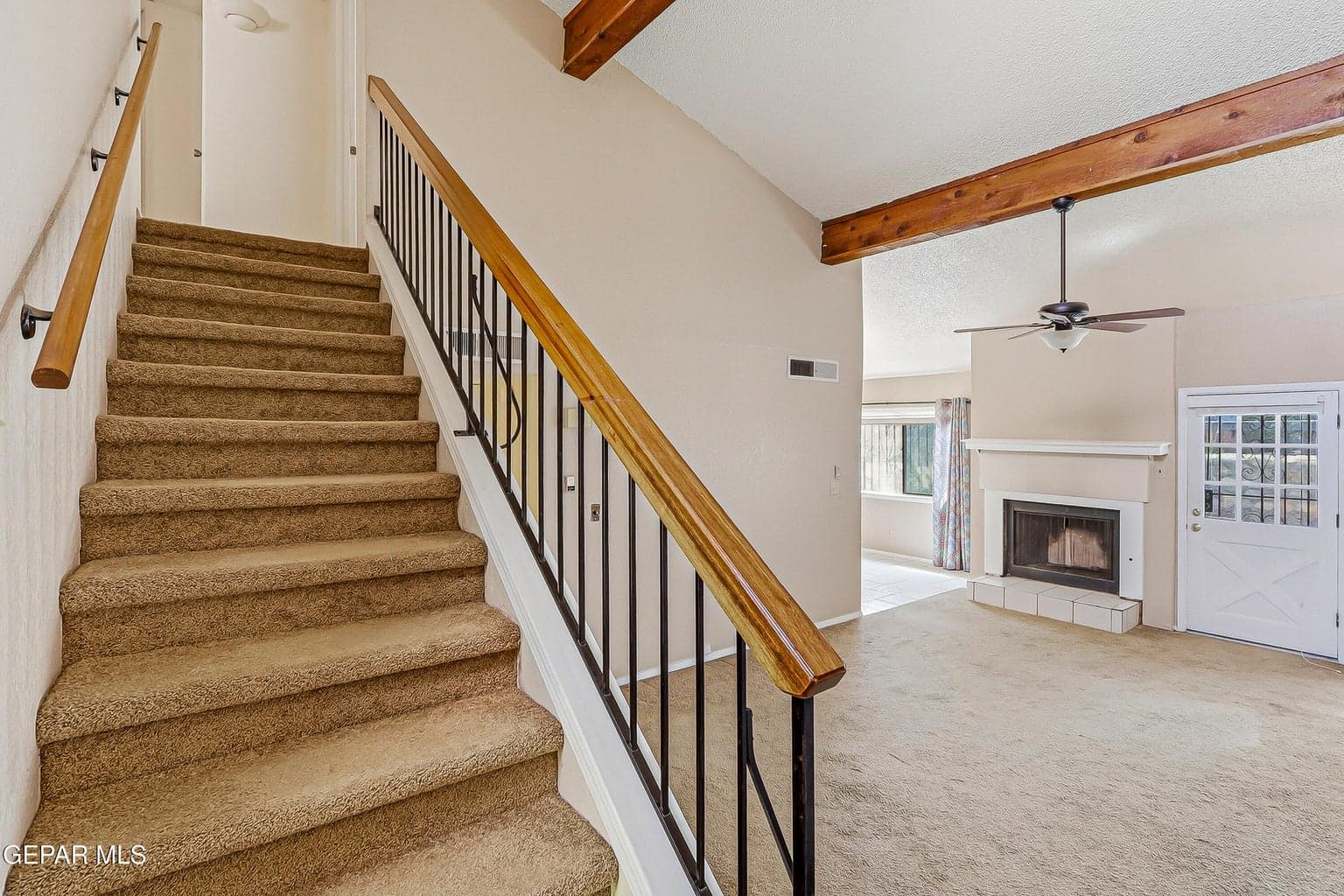 Carpeted staircase with wood handrails and black metal balusters