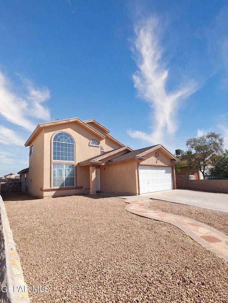 Two-story residence featuring a stucco exterior in warm earth tones, accented with a prominent arched window and pitched roofline -- digitally enhanced photo