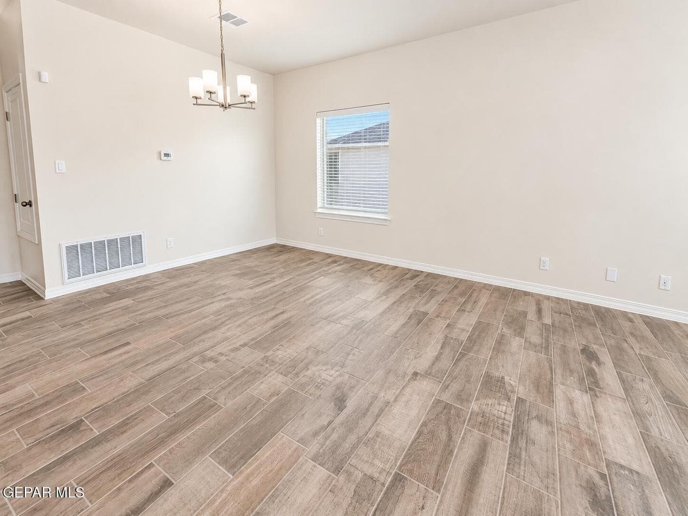 Dining space, neutral wall tones, a contemporary chandelier, and a single window with blinds