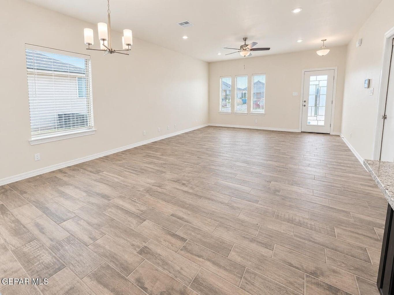 Spacious interior featuring wood-finish tile flooring, recessed lighting, and a ceiling fan