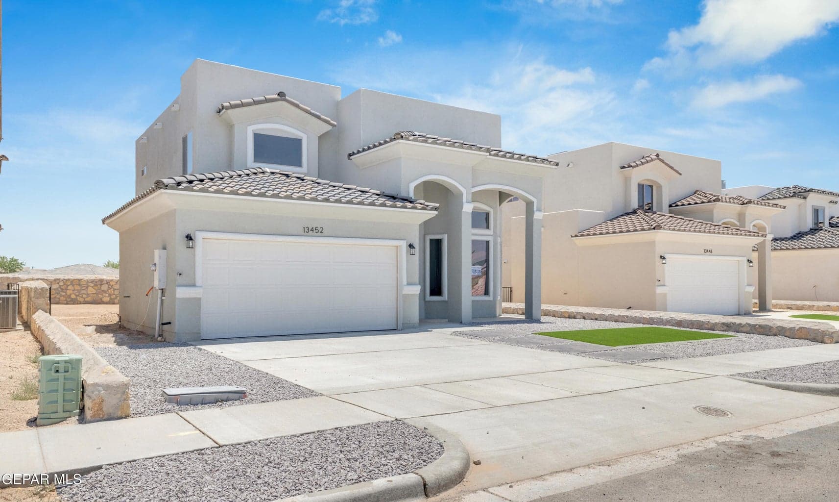 Stucco exterior with a tiled roof, arched entryway, and an integrated two-car garage