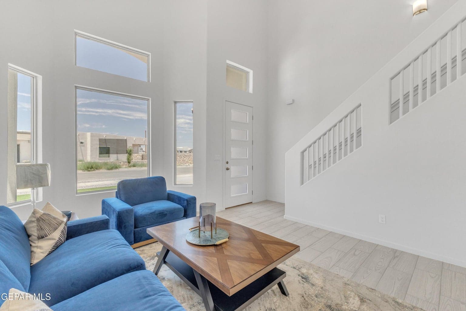 Vaulted ceilings, a contemporary entry door with frosted glass panels, and abundant natural light from multiple windows