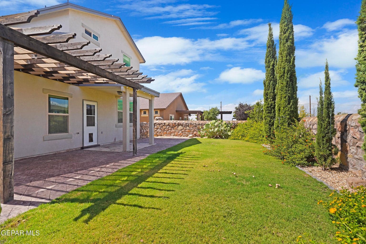 Walled backyard offers privacy with an open patio area ready for gatherings and outdoor enjoyment.
