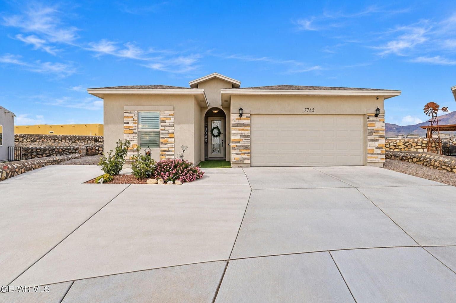 Stucco exterior featuring stone accents, an attached two-car garage, and a concrete driveway