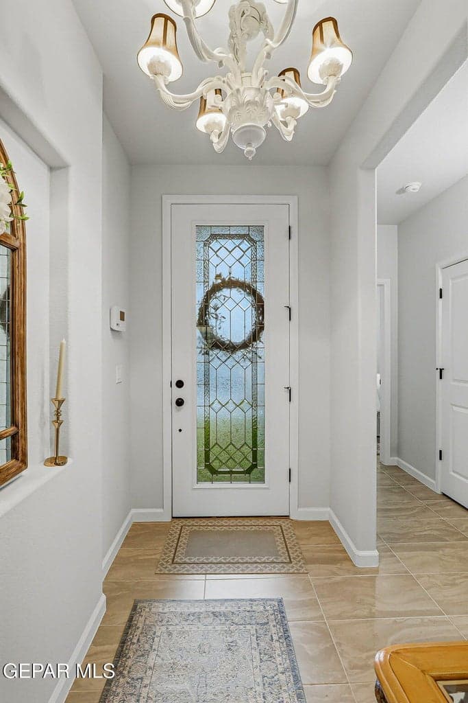 Foyer with decorative tile flooring, a glass-paneled entry door, and an ornate ceiling-mounted chandelier