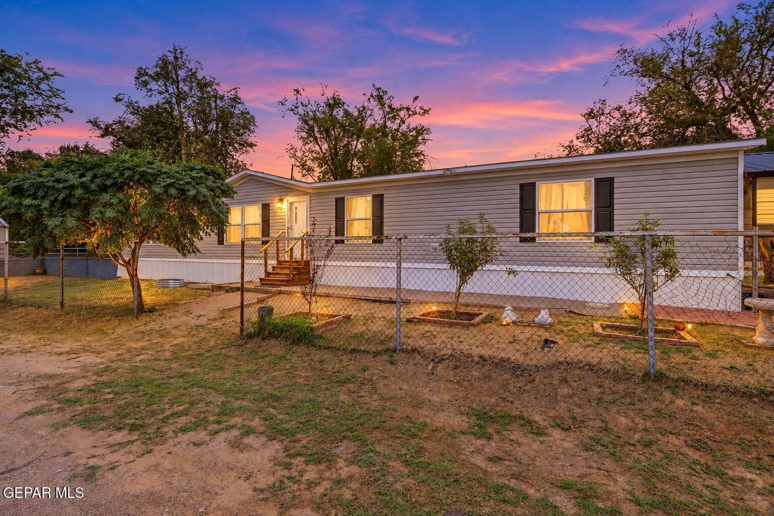 Siding exterior with dark shutters, front entry with wood steps, and a fenced front yard
