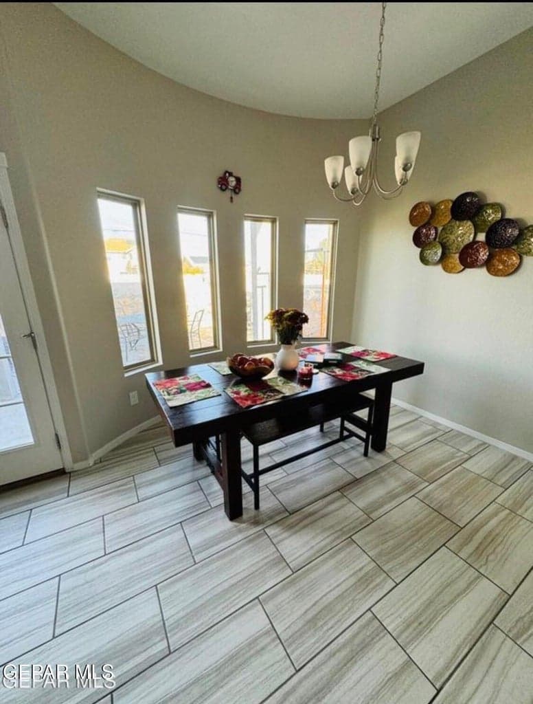 Curved wall architecture, multiple vertical windows, wood-finish tile flooring, and an overhead chandelier