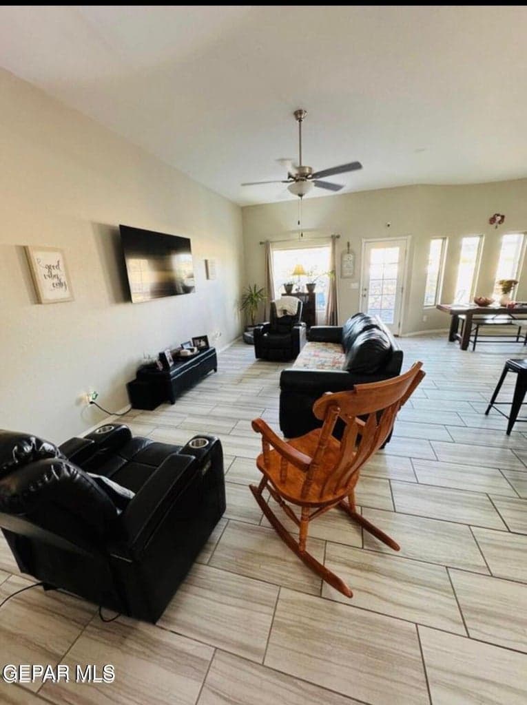 Tile flooring with a wood-finish pattern, ceiling fan with integrated lighting, multiple windows providing natural illumination, and a glass-paneled exterior door