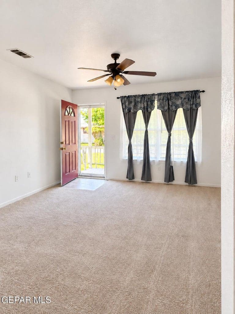 Bright living area with ample natural light and a storm door at the front entry.