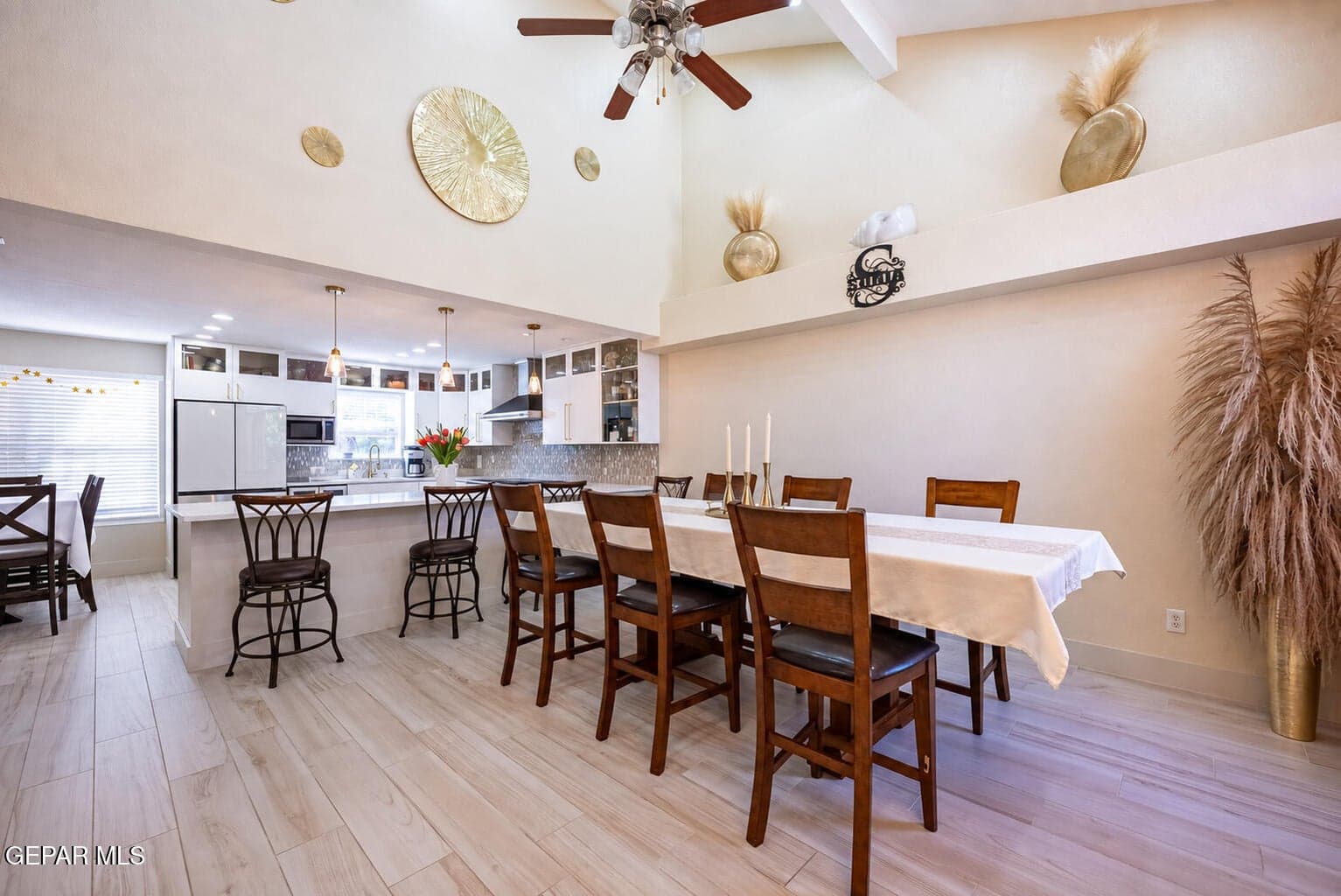 Vaulted ceiling with exposed beams, wood-finish flooring, kitchen island with counter seating, built-in cabinetry, and pendant lighting