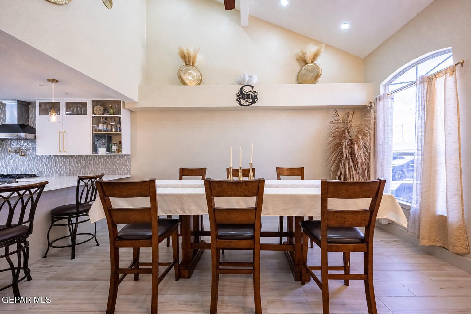 Vaulted ceiling and a high arched window, complemented by light wood-finish flooring