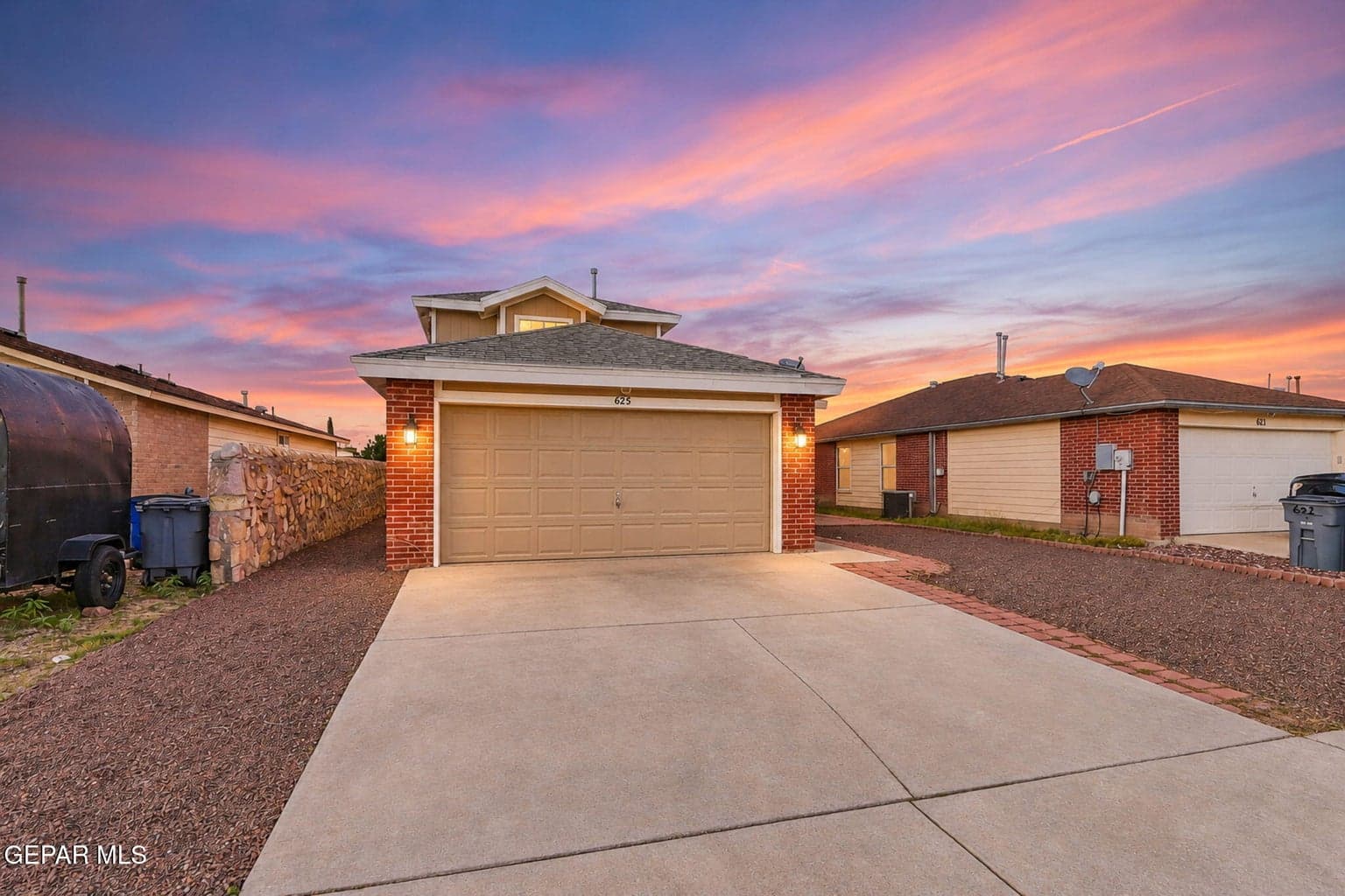 Two-story residence featuring a two-car garage, brick facade detailing, and a concrete driveway