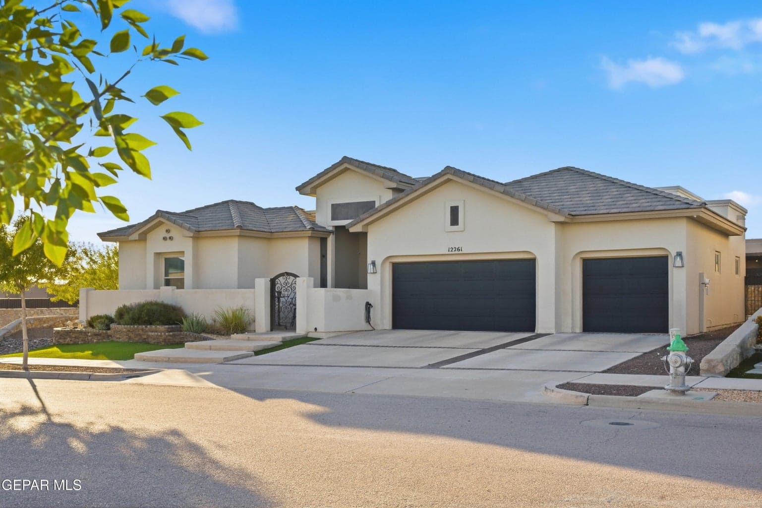 Stucco exterior with a tiled roof, three-car garage, and a gated entry