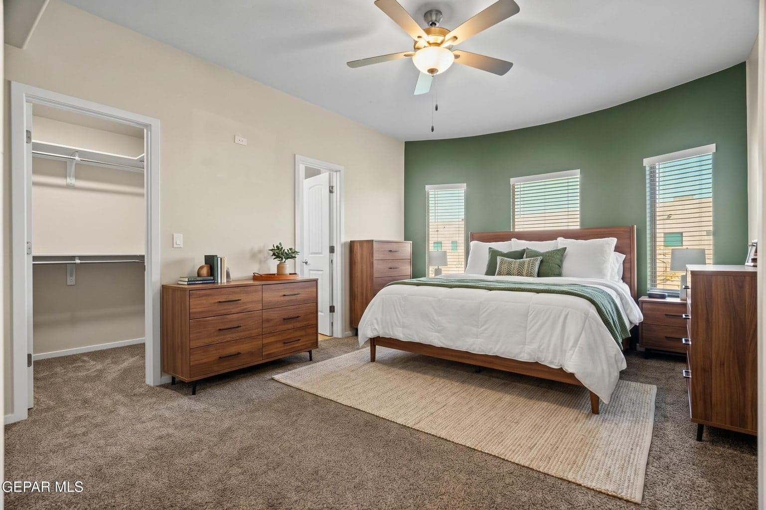 Unwind in a spacious primary suite featuring carpet flooring, large windows and a ceiling fan. This photo was AI generated to highlight the homes features and potential.