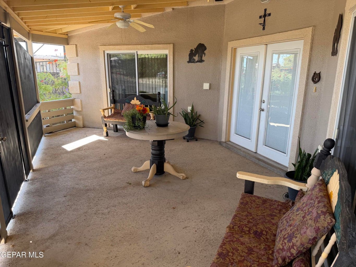 Covered patio featuring a concrete floor, ceiling fan, sliding glass door, and double glass-pane doors