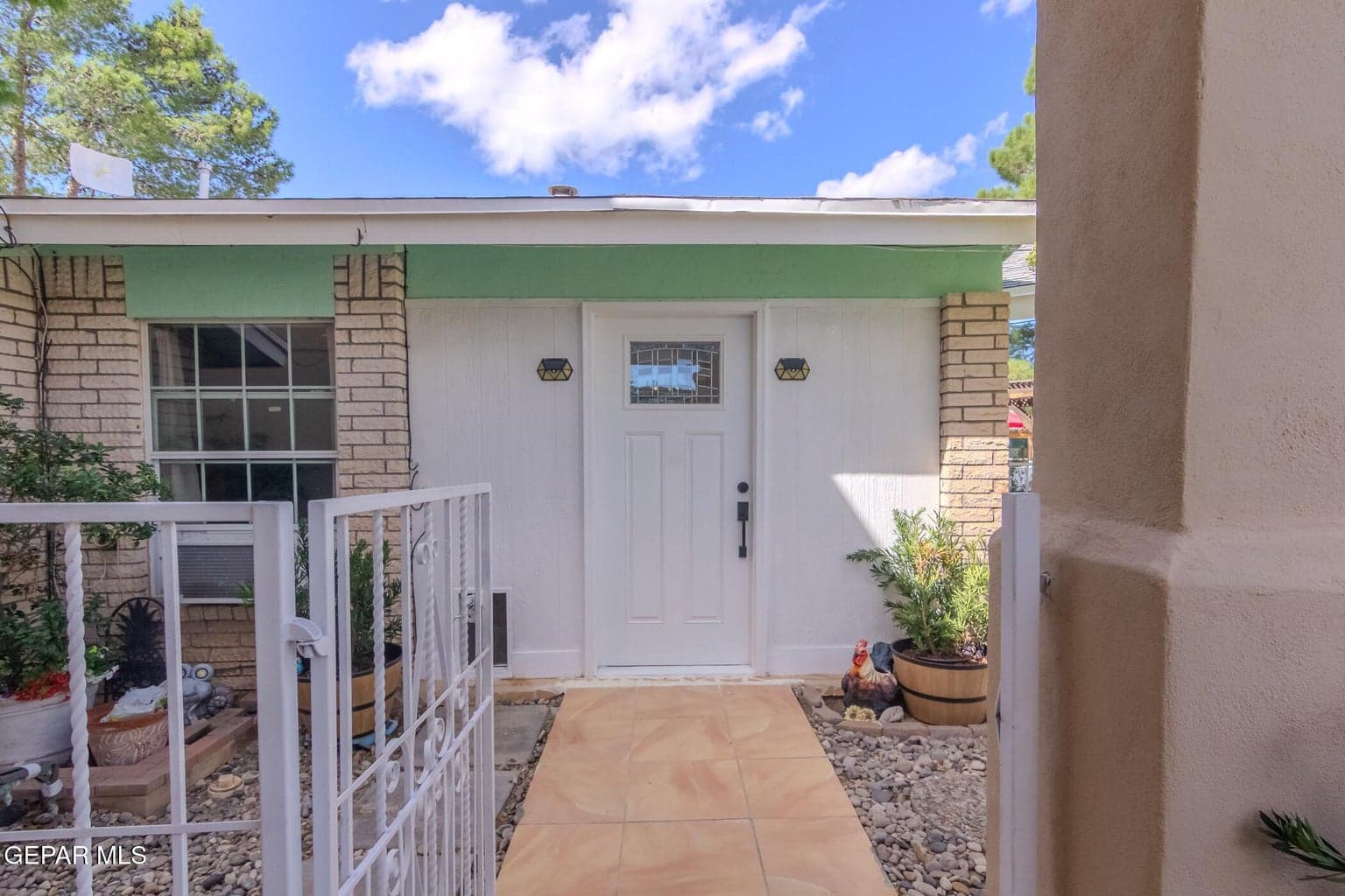 Main entrance to House #1, featuring a welcoming front walkway, gated access, and decorative landscaping.