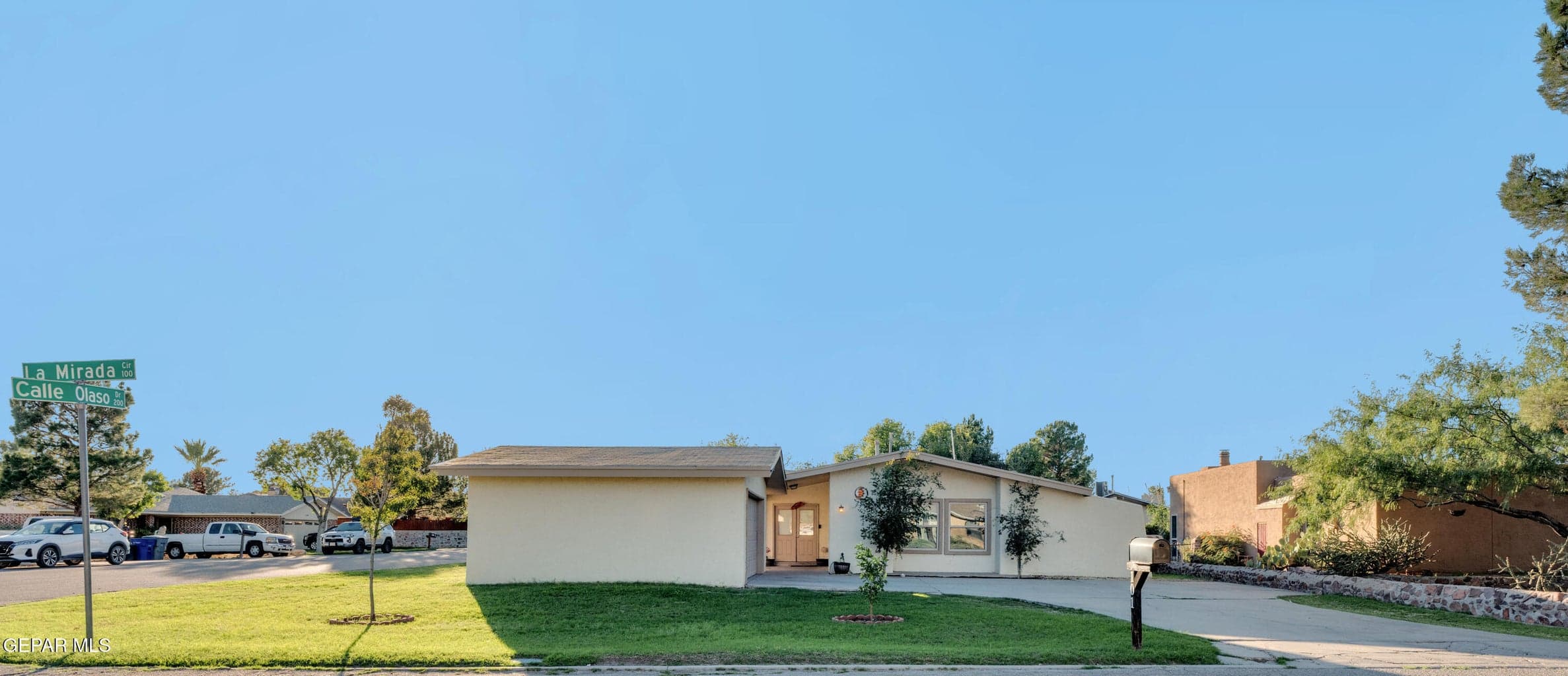 Single-story exterior featuring a low-pitch roofline, stucco siding, a paved driveway, and a front lawn