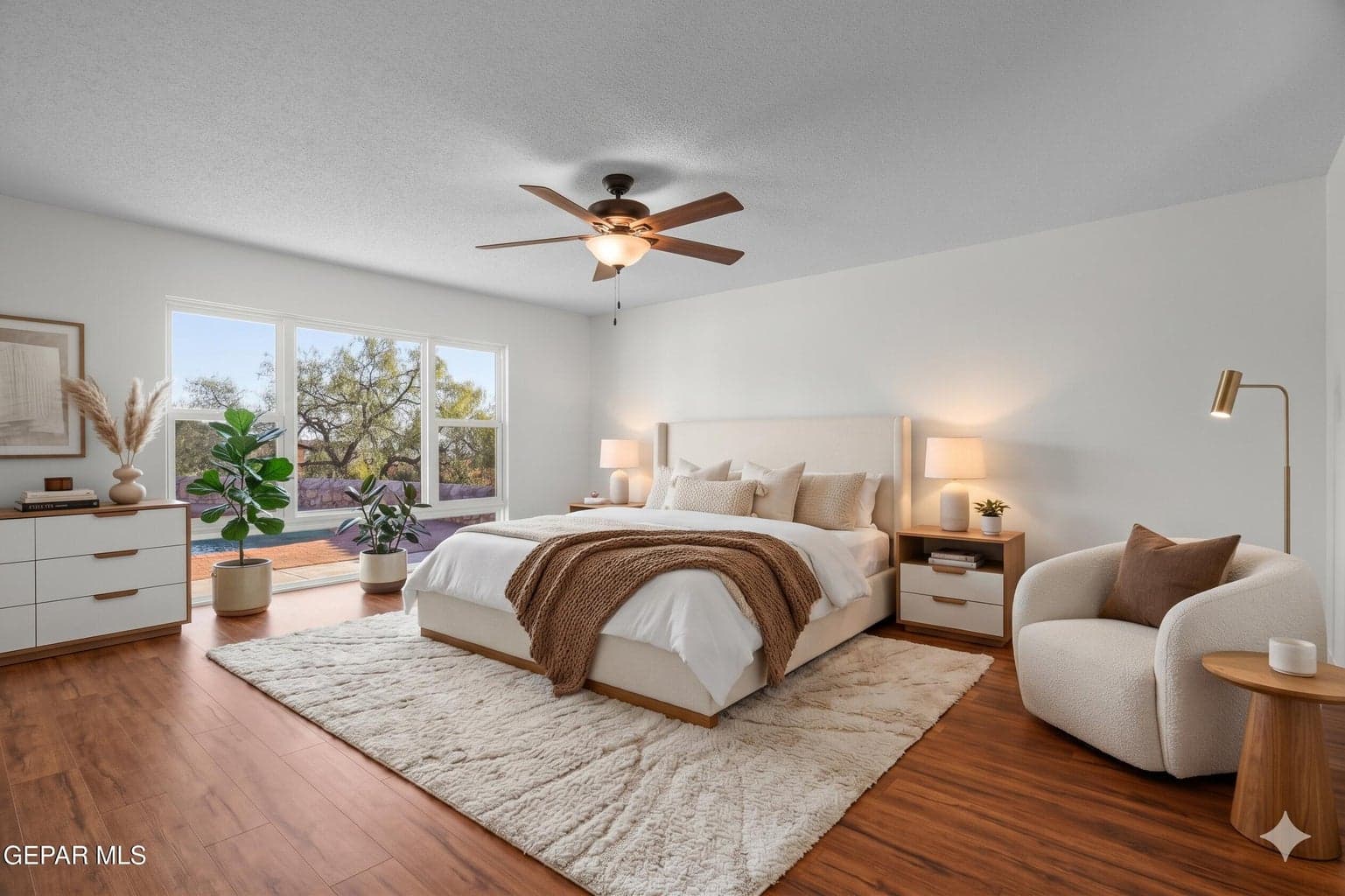 Unwind in a spacious primary bedroom featuring laminate flooring, a ceiling fan, and large windows that bring in natural light.