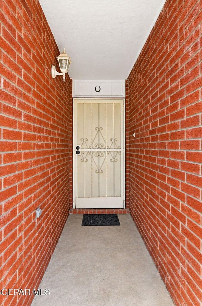 Private, brick-lined entryway with a decorative security screen door, perfect for welcoming the cool El Paso desert breeze.