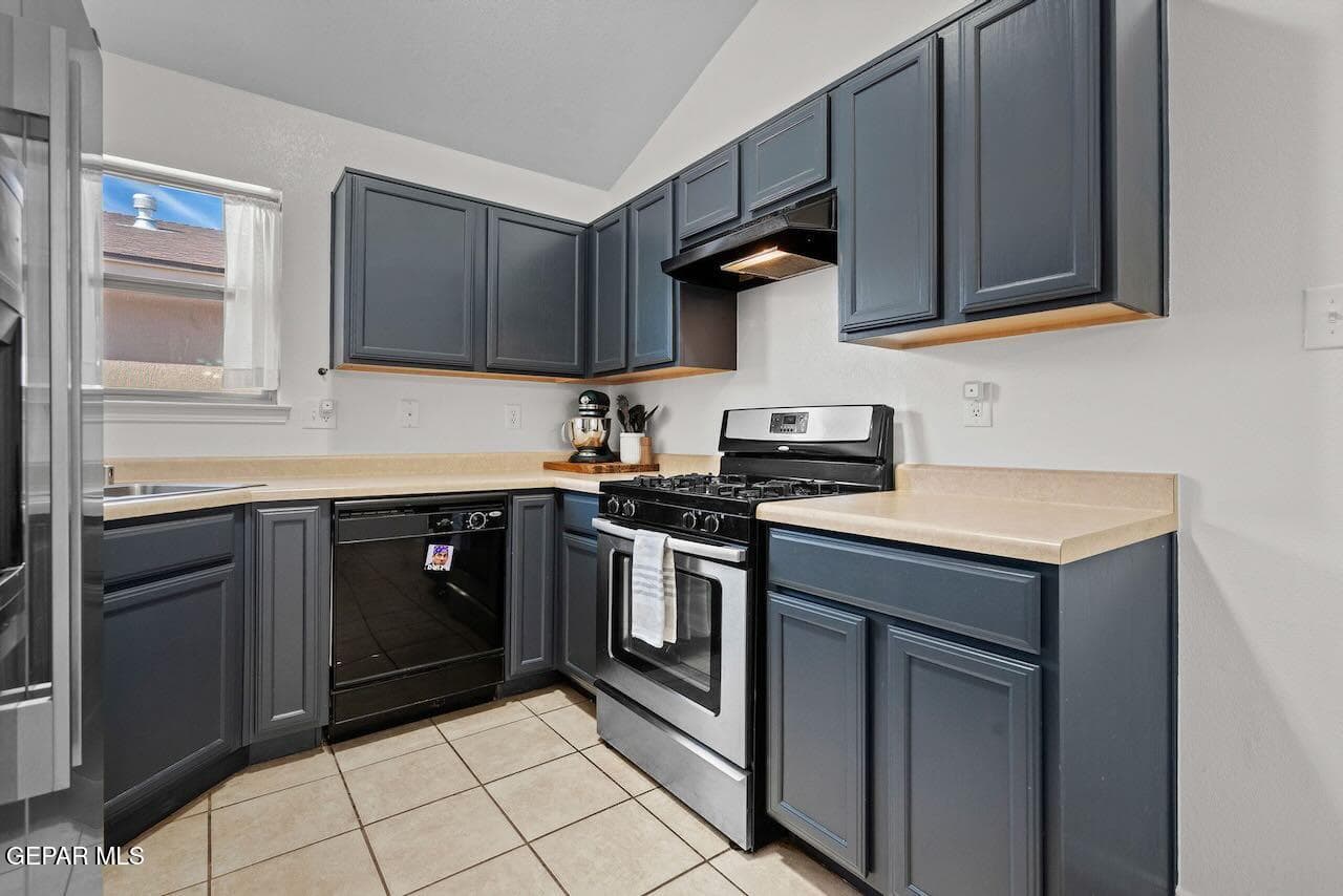 Kitchen featuring slate-toned cabinetry, stainless steel gas range, black dishwasher, neutral-tone laminate countertops, and tile flooring