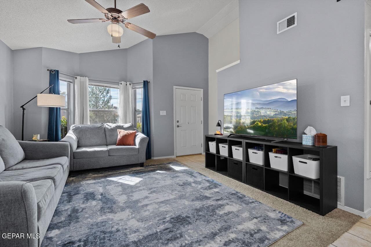 Vaulted ceilings, bay window, and a ceiling-mounted fan with integrated lighting